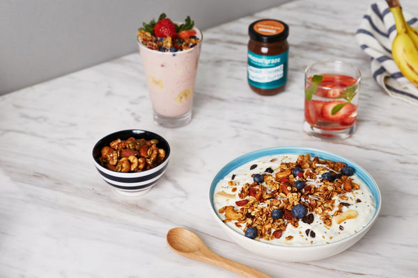 Amazin’ Graze granola bowl with smoothie, nuts, fruit water, and breakfast ingredients.