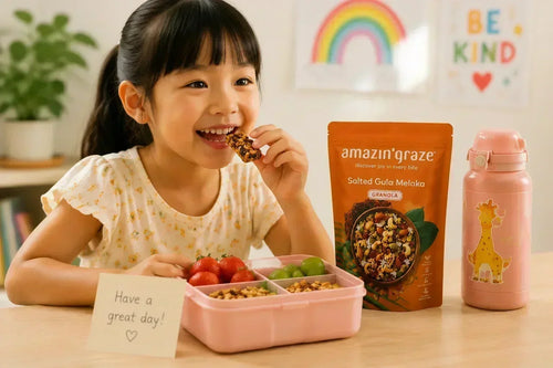 Amazin’ Graze granola beside a child’s lunchbox with fruit and a water bottle.