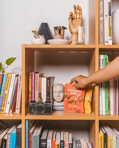 Amazin’ Graze granola, nut mixes, and protein blends displayed with fresh fruit for balanced snacking.